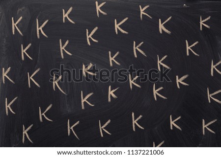 "K" letter written with chalk multiple times, school chalkboard spelling exercise