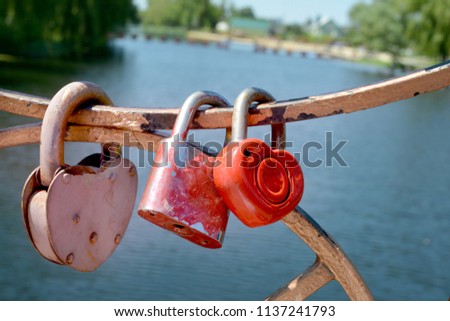 Metal locks on the iron fence of the bridge over the river as a wedding custom and a symbol of eternal love
