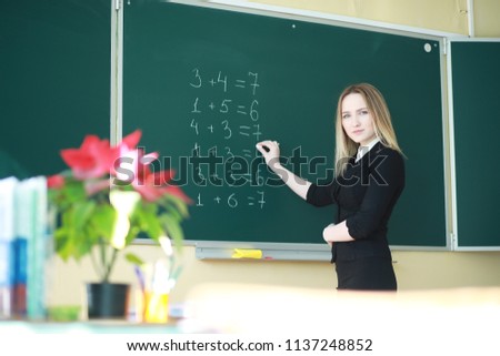 Young girl teacher in primary school in class in front of blackboard
