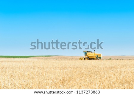 Harvester in the foreground on rustic background working in the field
