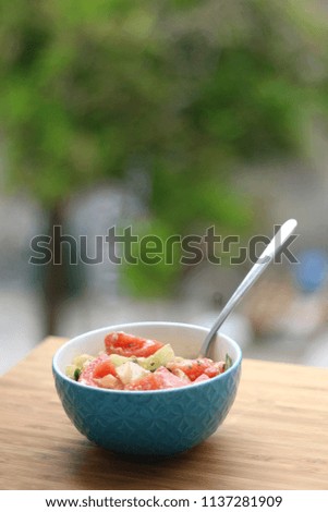 Turquoise colored bowl with vegetable and feta cheese salad. Ingredients are: tomatoes, cucumbers, fresh basil, olive oil and feta cheese. Selective focus.  