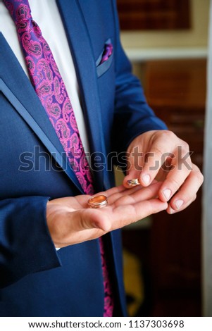 man groom holding in hands gold wedding rings on wedding day
