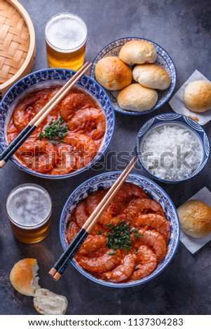 Spicy asian shrimps in tomato sauce with rice, buns and beer, top view