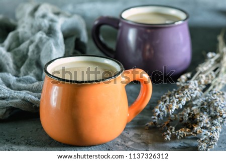 A small orange mug with coffee, next to dry lavender. Photo in the style of rustic. Nice picture.