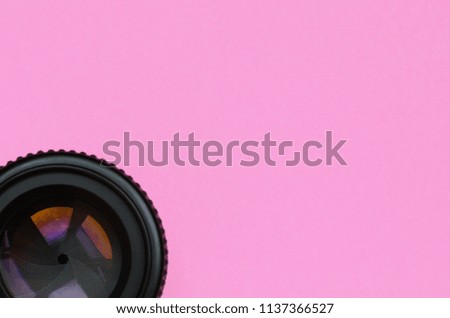 Camera lens with a closed aperture lie on texture background of fashion pastel pink color paper in minimal concept