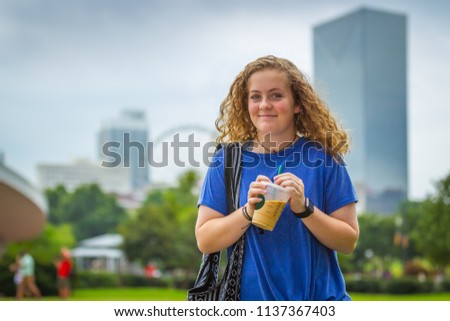 Young women standing in front of beautiful downtown Atlanta, Georgia cityscape background enjoying an iced coffee