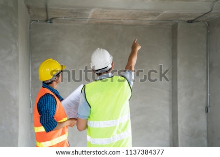 Civil engineer or architect and worker with safety helmet checking building ,engineering and architect concept.Blue print is fake only for stock photo.