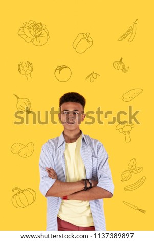Hungry person. Calm young boy standing with his arm crossed and thinking about food while being hungry