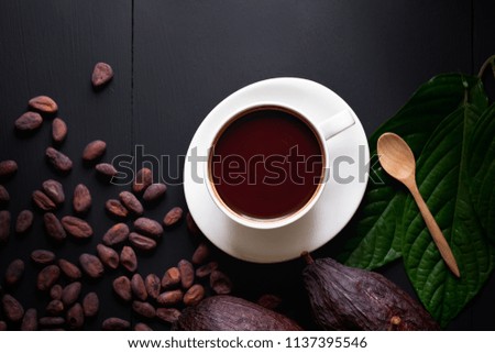 Hot chocolate and Cocoa pod cut exposing cocoa seeds on dark table, top view with copy space.