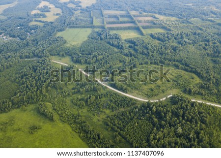 Helicopter drone shot. Aerial photography of green forest with road, green grass.