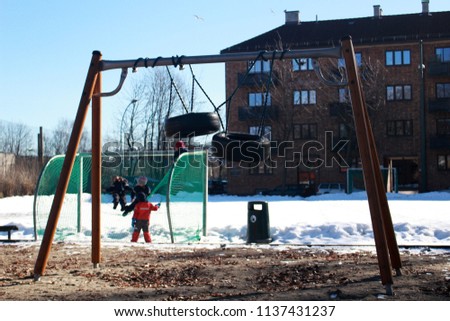 A couple of tire swings are tangled together at this playground in central Oslo as kids play in the snow in the background.