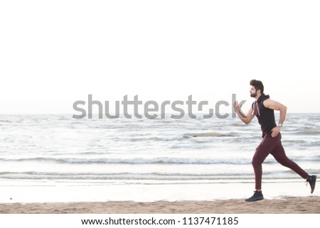 Fit young man jogging along the beach Royalty-Free Stock Photo #1137471185