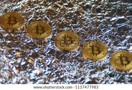 coins of bitcoin lie in the background of the foil