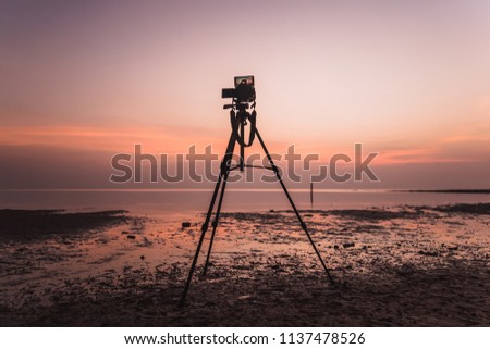 Photographing a seascape. Mirror camera on a tripod removes the dawn of the sea. A bright pink dawn.