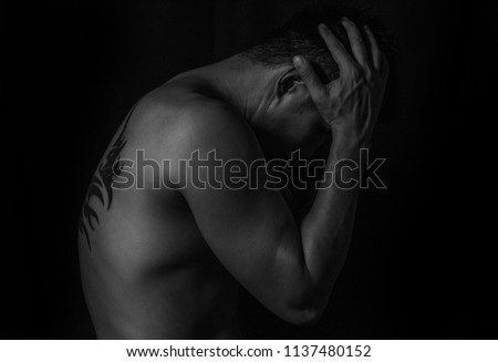 Sad and worried man from major depressive disorder, Asian male have back tattoo sad and worry negative thinking from MDD. Black and white color picture body man side view.