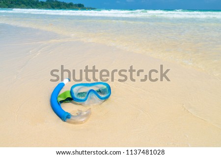 Blue classic snorkeling mask with blue plastic tube on white sand on beautiful sea landscape background. Andaman and Nicobar Islands. India