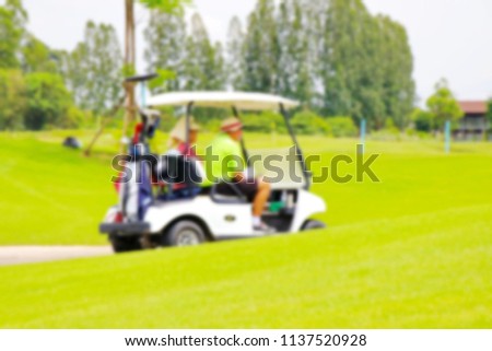 Golf carts in the golf course are blurry.