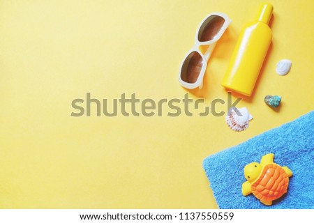 Flat lay summer travel photo. Trendy sunglasses, yellow sunscreen bottle, seashells, blue towel and turtle toy. Beach essentials for sea rest