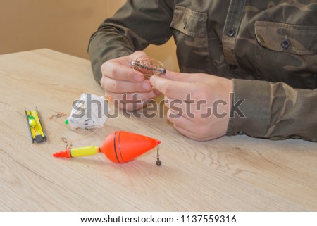 Fishing rod and spinnings in the composition with accessories for fishing on the background on the table. Close-up of a fisherman's hands with Fishing tackle