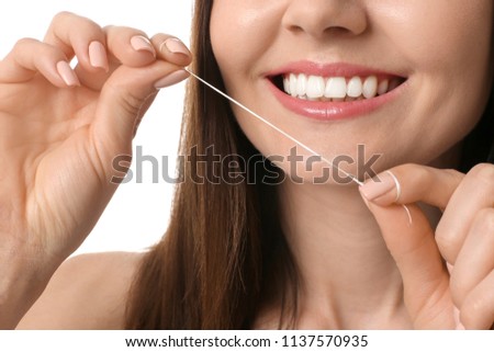 Young woman flossing her teeth on white background