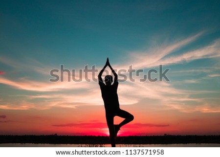 Silhouette of young man yoga in the sunset.
