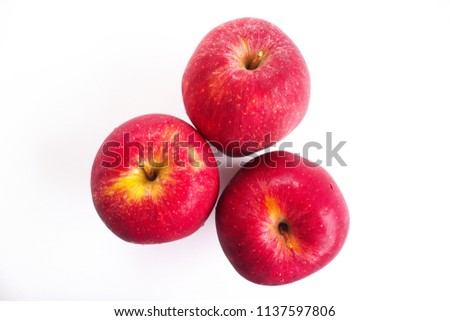 Three red apples placed on a white background showing its color and shape. The shot taken with a high angle view. The fruit is edible, and it has a significant meaning in Christian tradition