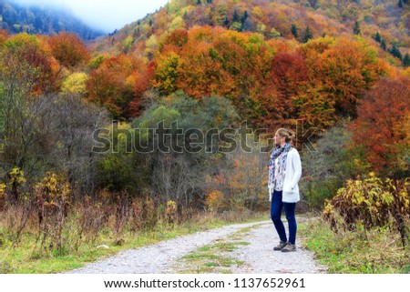 Beautiful young woman hikes in the forest in the mountains of the Rila Nature Park in Bulgaria with vibrant autumn colors