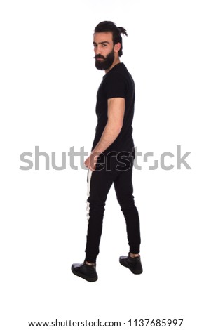 Full-length back shot of a standing long bearded man looking to the camera, isolated in a white background.