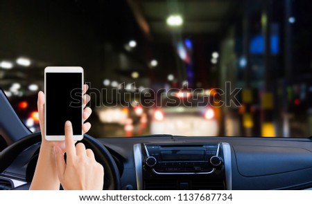 woman use mobile phone in the car when stop the car at the barrier gate checkpoint at night