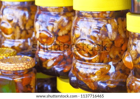 Honey with nuts in jars standing on each other at a fair market