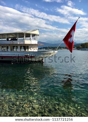 A boat on the lake in Lucerne, Switzerland. Switzerland flag and Alps in the background.