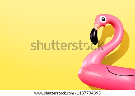 Giant inflatable Flamingo on a yellow background, pool float party, trendy summer concept