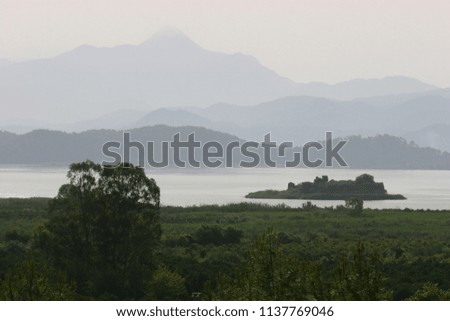 River effusing in big lake and wetland, fog diffuses the mountains in the background