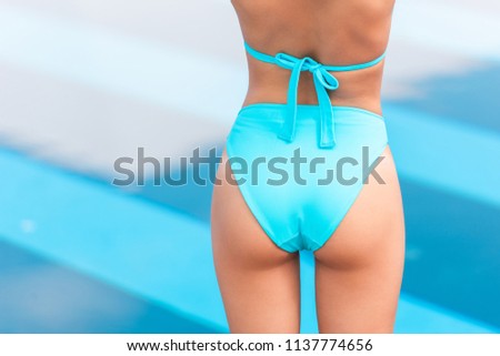 cropped back view of tanned female butt in blue bikini 