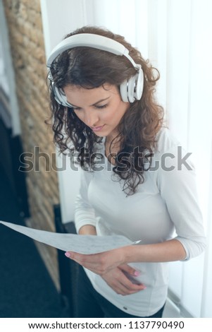 Young woman listen music during reading something at her office