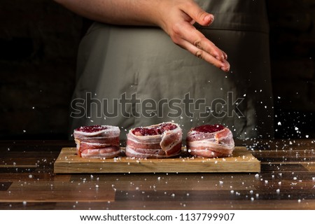 Cooking beef meat fillet mignon on wooden table by cook hands, copy text black background.