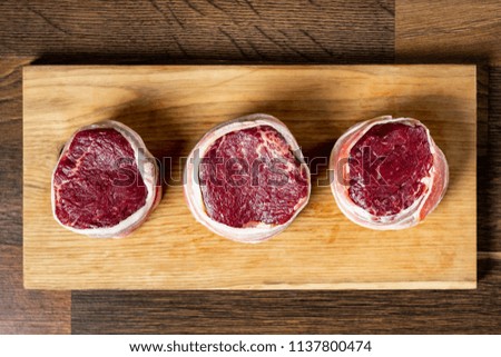 Cooking beef steak marble meat for dish fillet mignon in bacon. Wooden background. Flat lay, from above.