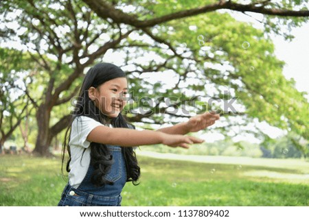 Children's play concept. The girl is playing blowing bubbles in the garden. The girl smiles happily in the park.