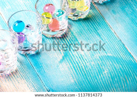 in the corner of the frame shot glasses under vodka in which colored balloons are filled, blue color of boards on which there are glasses