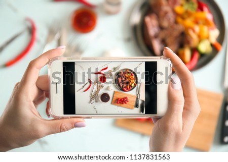 Woman taking photo of barbecue sauce and grilled meat with mobile phone, top view
