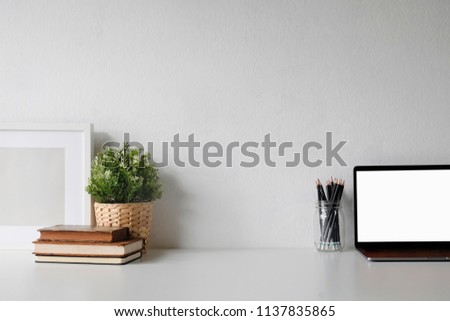 Workspace with laptop computer and book on white table.