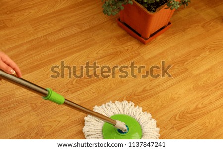 cleaning wooden floor with green wet mop. Royalty-Free Stock Photo #1137847241