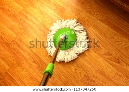 cleaning wooden floor with green wet mop. Royalty-Free Stock Photo #1137847250