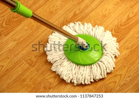 cleaning wooden floor with green wet mop. Royalty-Free Stock Photo #1137847253