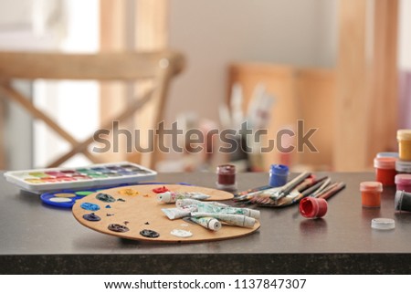 Different color paints and wooden palette on table