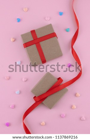 Brown gift boxes and red ribbon decorate with pastel heart pattern on pink background 