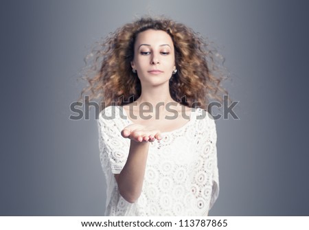 beautiful young woman presenting something on blue background.shallow depth of filed with hand in focus.