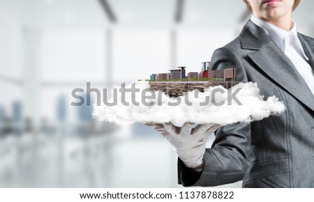 Cropped image of waitress's hand in white glove presenting modern city block on metal tray with office view on background. 3D rendering.