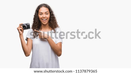 Young hispanic woman taking pictures using vintage camera very happy pointing with hand and finger