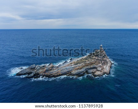 Layered rocky island with a lighthouse.